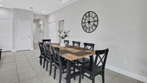 A dining area with a wooden table and black chairs, a wall clock, and a white vase with flowers. - 163KB - Balmoral Resort, a spacious 4-bedroom retreat perfect for families (Haines City)
