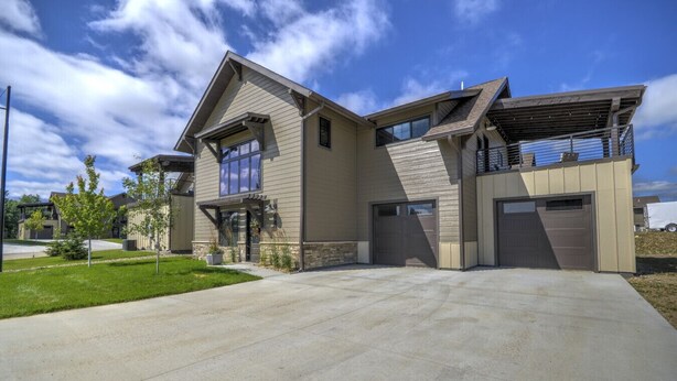 A modern two-story house with a garage, a covered patio, and a well-maintained lawn.