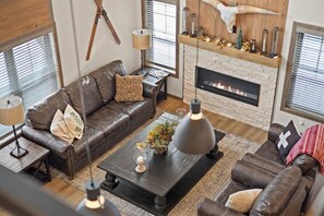 Una sala de estar acogedora con chimenea, sofás de cuero y una mesa de centro con objetos decorativos.