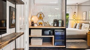 A modern hotel room with a marble floor, a bed with multiple pillows, a built-in air conditioning unit, a wooden shelf with storage baskets, and a wall-mounted TV. - El Mirador; Unit E (Palm Springs)
