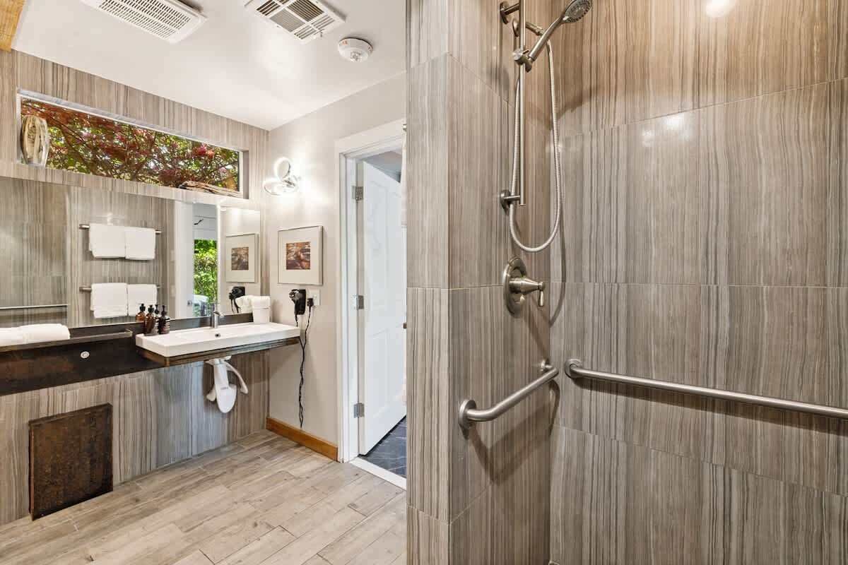 A modern bathroom with a large mirror, a sink, and a shower area.