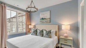 A bedroom with a large bed, two bedside tables with lamps, a window with curtains, and a painting on the wall. - The Manor 93 A&B - 2 Newly Renovated Units in Downtown Charleston! (Charleston)