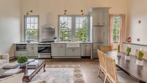 A modern kitchen with white cabinets, a central island, and a dining area with a table and chairs. - The Manor 93 A&B - 2 Newly Renovated Units in Downtown Charleston! (Charleston)