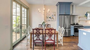 A modern kitchen with a dining area, featuring a large window, stainless steel appliances, and a chandelier. - The Manor 93 A&B - 2 Newly Renovated Units in Downtown Charleston! (Charleston)