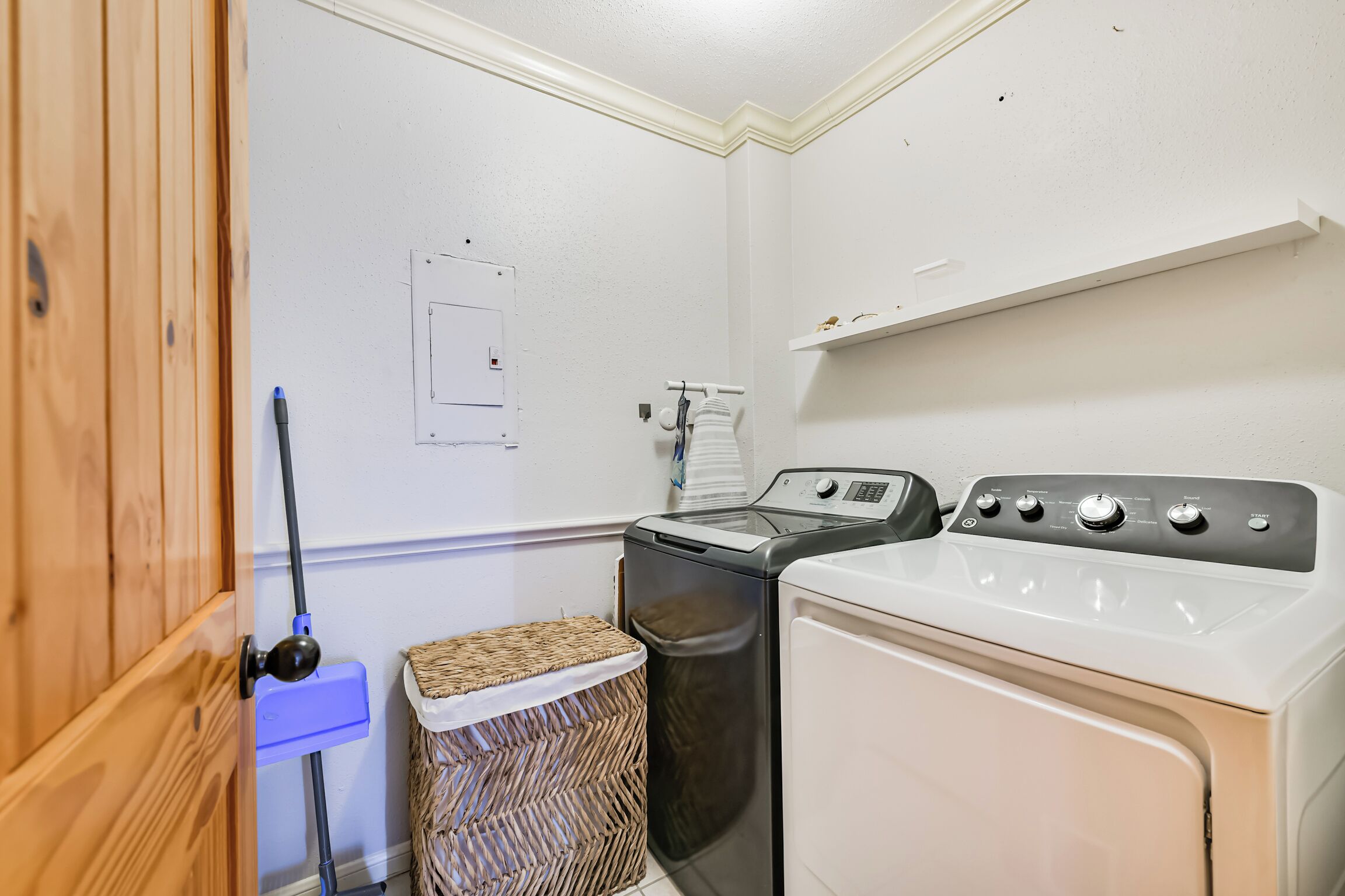 A laundry room with a washing machine, dryer, and a wicker basket.