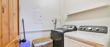 A laundry room with a washing machine, dryer, and a wicker basket.