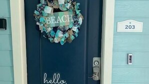 A dark blue door with a 'hello' sign and a 'BEACH' sign on a wreath.