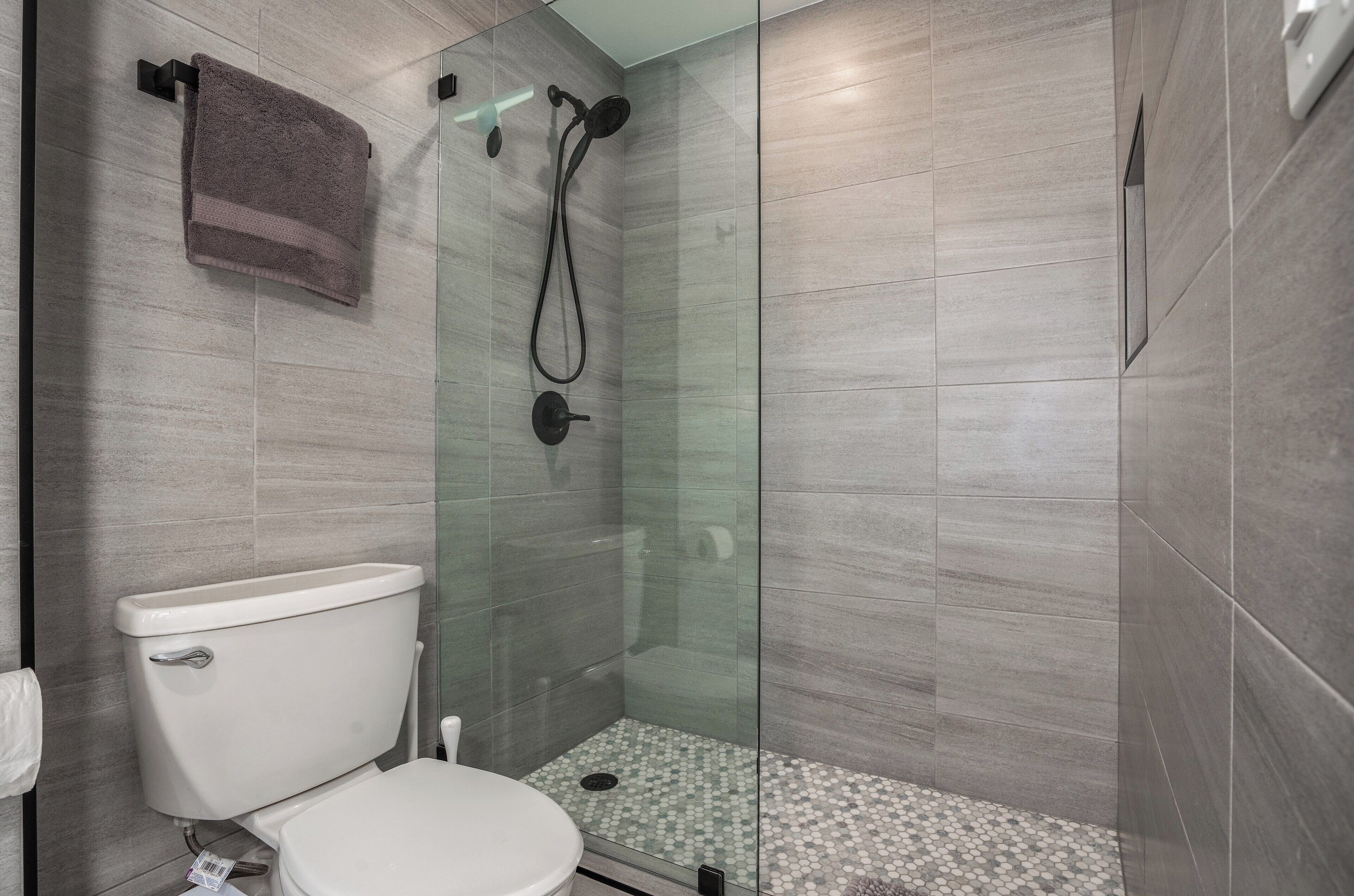 A bathroom with a glass-enclosed shower, a toilet, and a towel hanging on a rack.