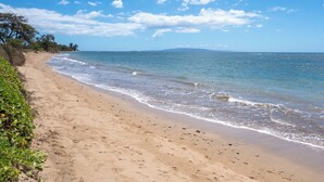 A sandy beach with gentle waves, clear skies, and distant land. - Hip Hawaiian Seaside Vistas (Kihei)