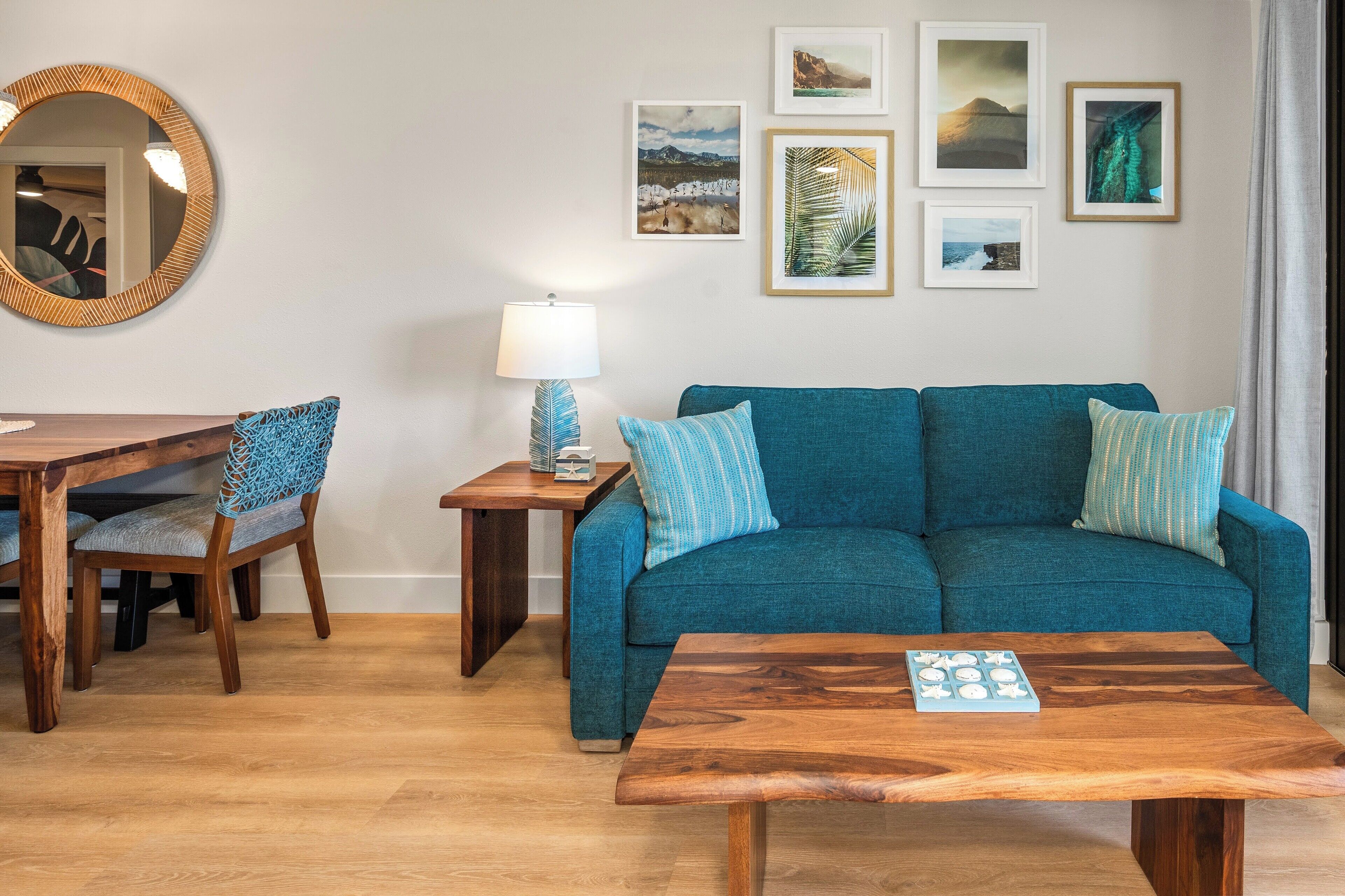 Un salon avec un canapé bleu, une table basse en bois et un coin repas comprenant une table et des chaises en bois.