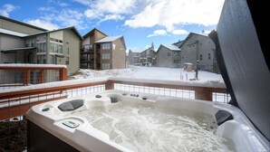 Ein Whirlpool mit Blick auf eine verschneite Landschaft und Gebäude im Hintergrund.