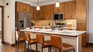 Eine moderne Küche mit Holzausstattung, Edelstahlgeräten und einer zentralen Kochinsel mit Barhocker.