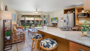 Una cocina moderna con una isla grande, taburetes de bar y un comedor con vistas al exterior.