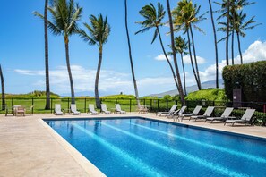 Una piscina al aire libre, sillones reclinables de piscina