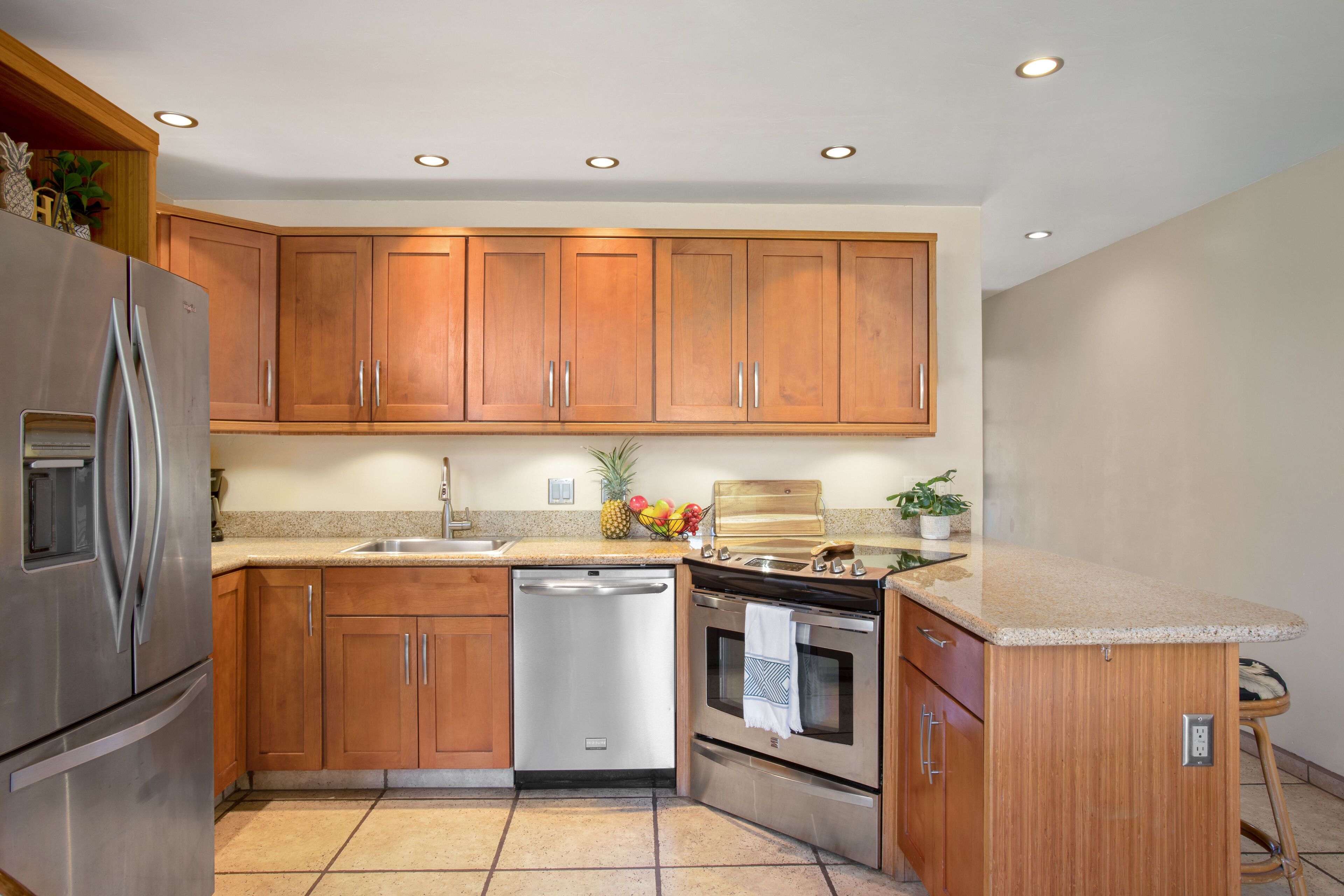 A kitchen with wooden cabinets, stainless steel appliances, a dishwasher, and a granite countertop.