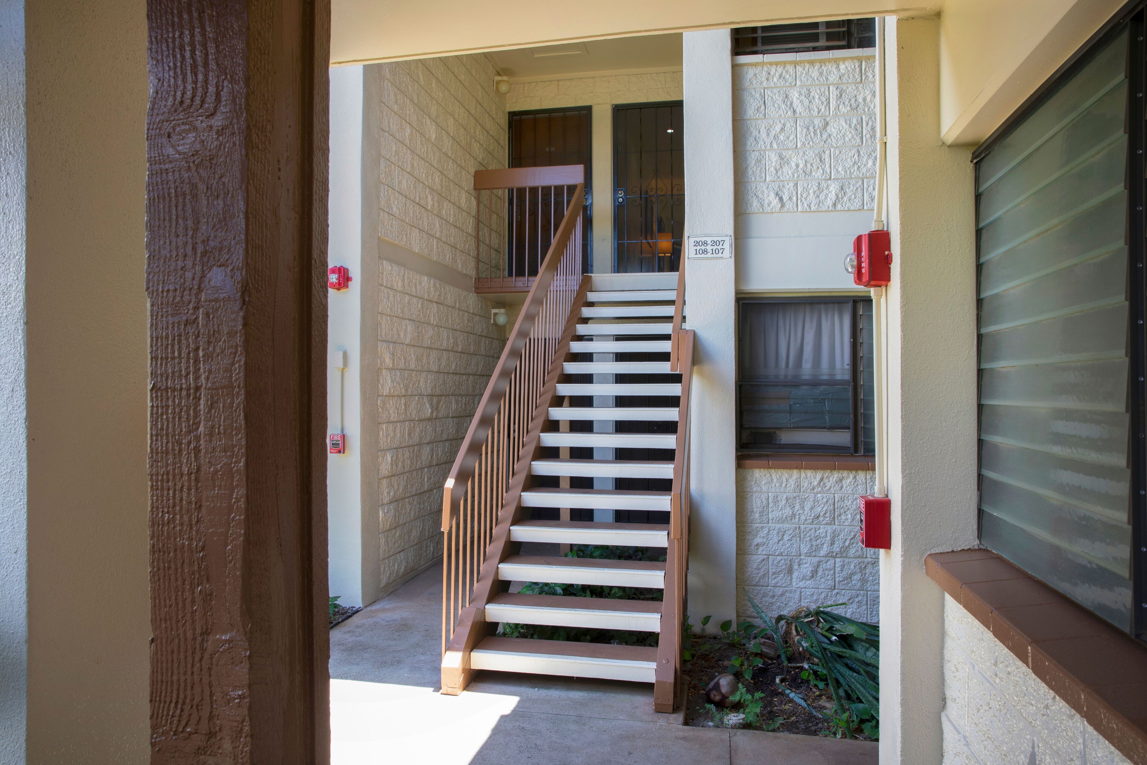 A staircase leading to an apartment entrance with a brick wall and a window with blinds.