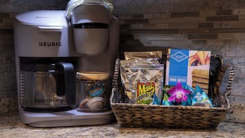A Keurig coffee maker, a basket of coffee bags, and a jar with a lid on a kitchen counter.