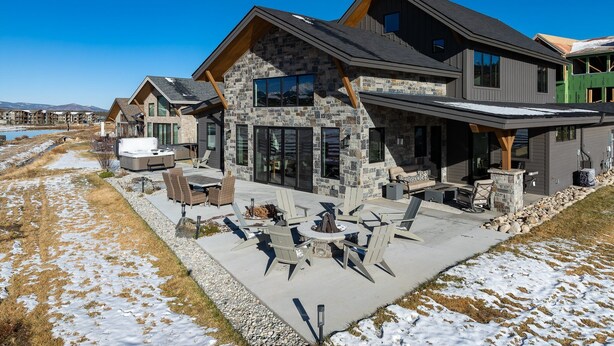 Una casa moderna con fachada de piedra, ventanas amplias y un patio con mobiliario exterior.