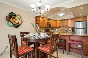 Een moderne keuken met houten kastjes, roestvrijstalen apparatuur en een eethoek met een ronde tafel en stoelen.