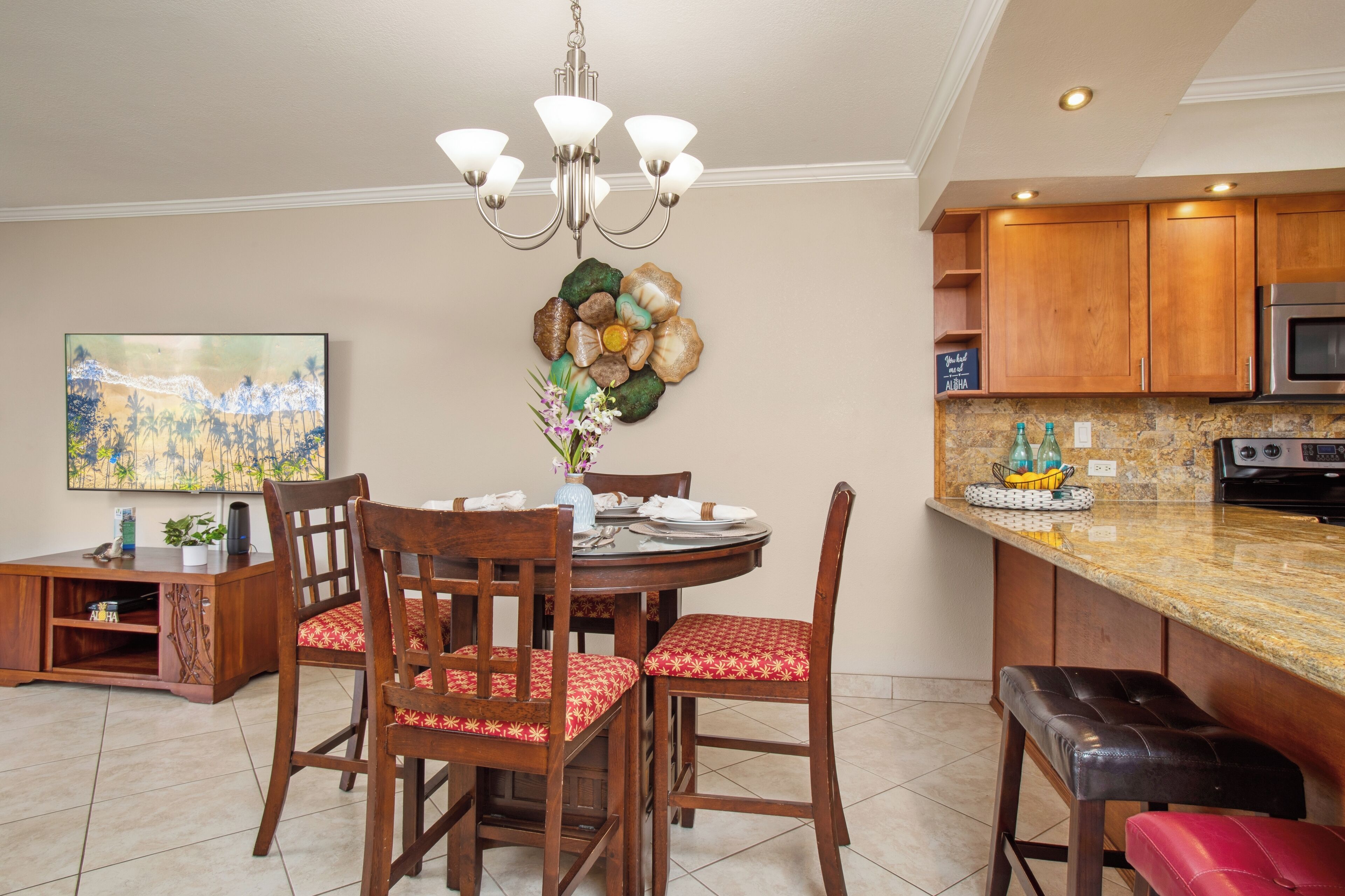 A dining area with a round table, wooden chairs, and a chandelier.