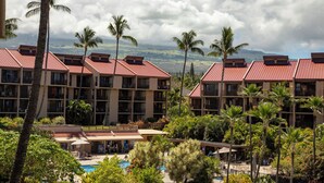 A hotel with multiple buildings, a swimming pool, and palm trees. - Kamaole Sands Condos Close to Beach with Parking (Kihei)