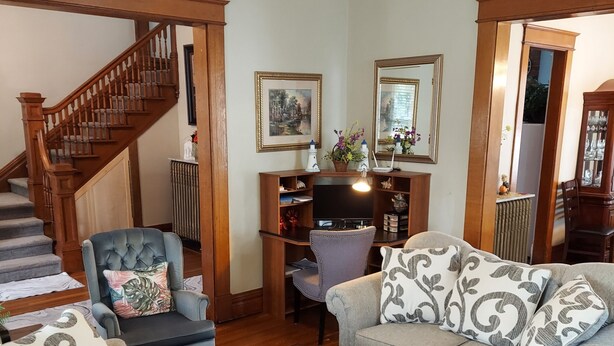 A living room with a staircase, a television, and a coffee table. - Charming historical 4 bd & 3 full ba home in Terre Haute with WiFi, AC & parking (Terre Haute)