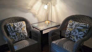 Two wicker chairs with patterned cushions, a small glass table, and a floor lamp. - Charming historical 4 bd & 3 full ba home in Terre Haute with WiFi, AC & parking (Terre Haute)