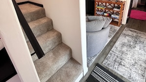 Un escalier menant à un espace de vie comprenant un canapé et une table basse.