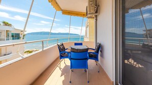 A balcony with a table and chairs, overlooking a coastal view. - Kondo Stays - Bliss Apartment (Vlorë)