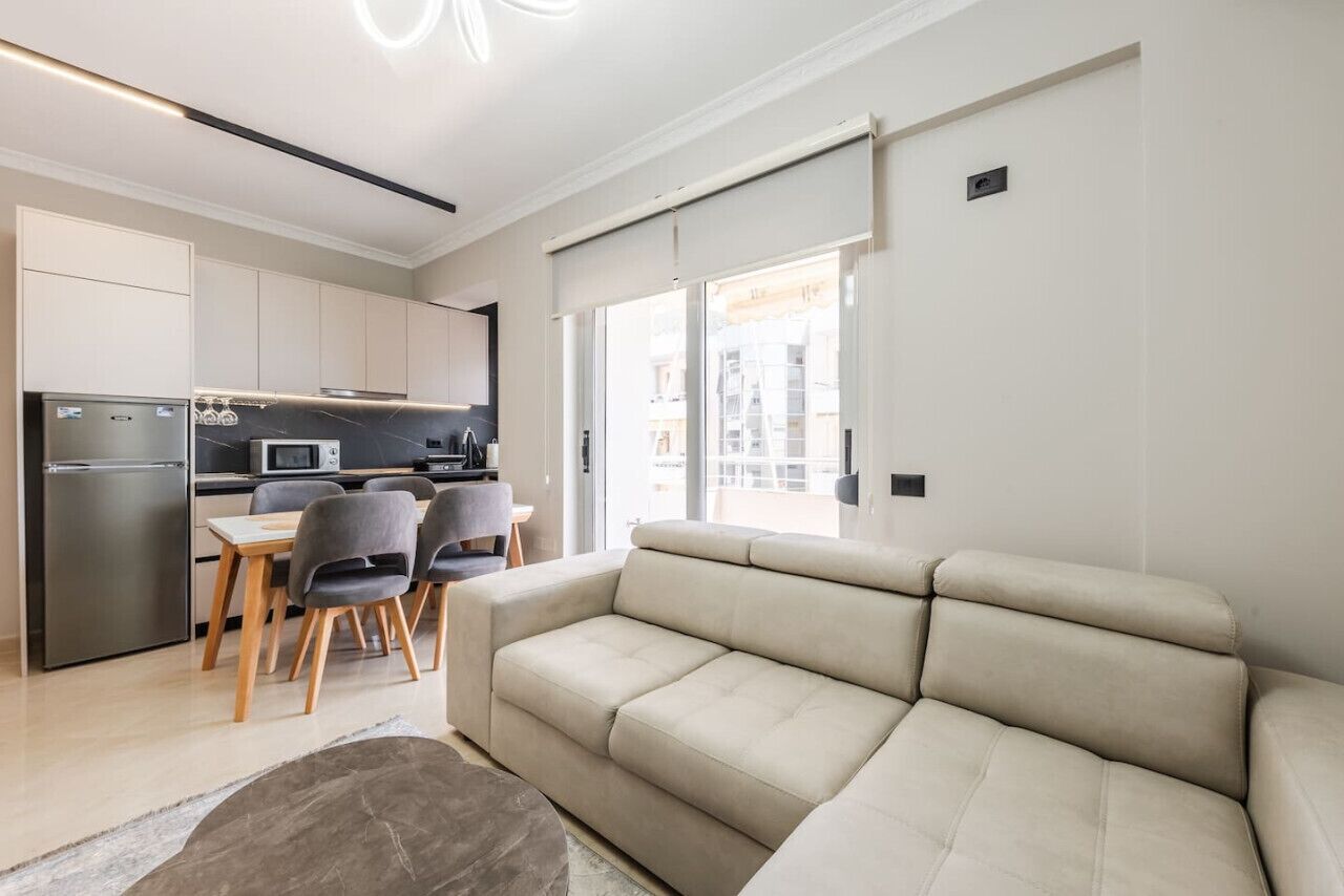 A modern kitchen with a refrigerator, microwave, and dining area with chairs and a table.