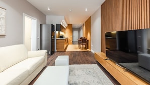 A modern living room with a sofa, a TV, and a wooden accent wall.