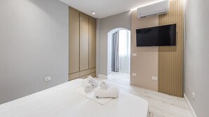 Une chambre d’hôtel moderne dotée d’un grand lit, d’un téléviseur à écran plat fixé au mur et d’un système de climatisation.