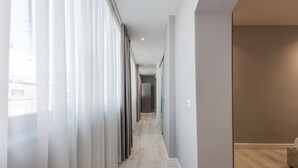 Un long couloir étroit doté d’un plancher en bois de couleur claire et de murs blancs.