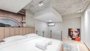 Ein modernes Schlafzimmer mit einem großen Bett, einer gläsernen Dusche und einem Bild an der Wand.