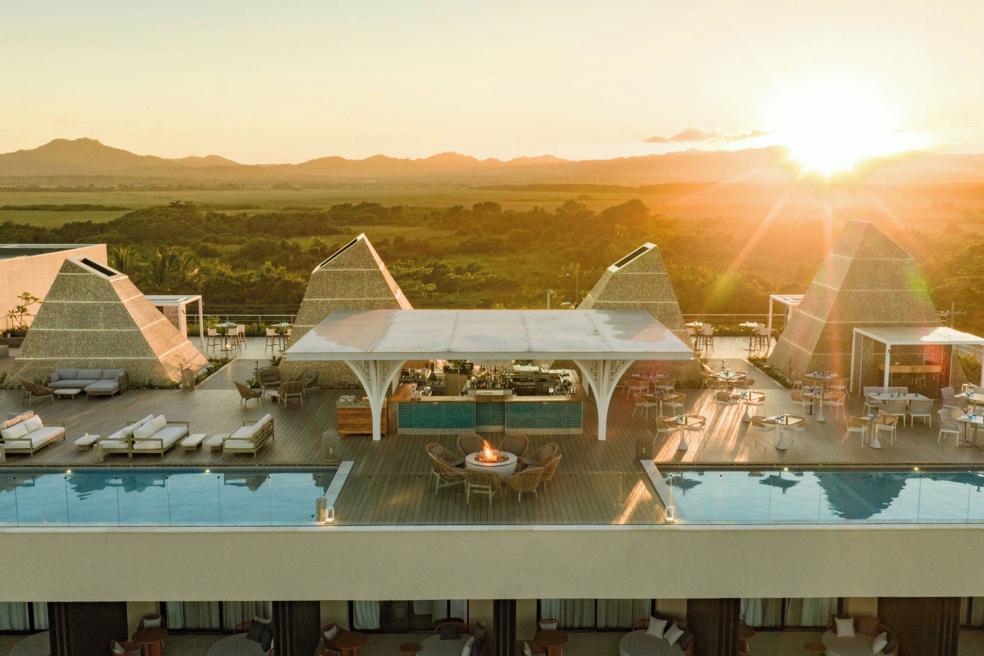 Área de piscina en la azotea con sillones, un bar y vistas al paisaje.
