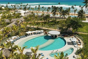A resort with a large pool, palm trees, and a beach view. - W Punta Cana, Adults (Punta Cana)