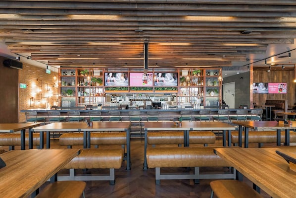 A restaurant interior with wooden panel ceilings, a bar area, and seating arrangements. - Sandman Signature Winnipeg Airport Hotel & Suites (Winnipeg)