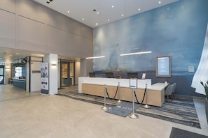 A modern reception area with a reception desk, a coffee station, and a large wall mural.
