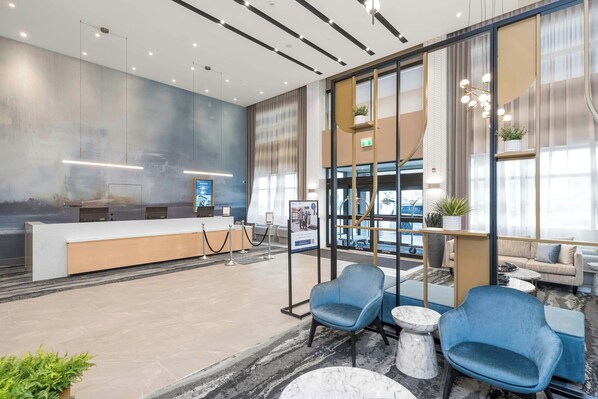 Un moderno vestíbulo de hotel con mostrador de recepción, zona de estar y amplios ventanales.