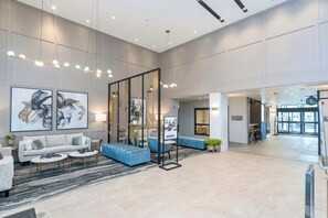 A spacious lobby with a modern design, featuring a seating area with sofas and a coffee table, a large abstract painting, and a reception desk. - Sandman Signature Winnipeg Airport Hotel & Suites (Winnipeg)