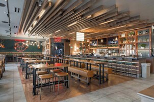 Interior de restaurante con vigas de madera, mesas y una zona de bar.