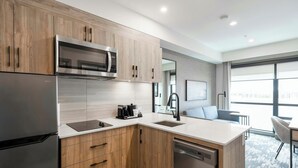 A modern kitchen with stainless steel appliances, wooden cabinets, and a built-in dishwasher.