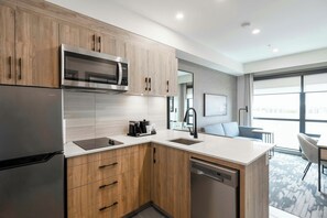 Una cocina moderna con electrodomésticos de acero inoxidable, armarios de madera y lavavajillas empotrado.