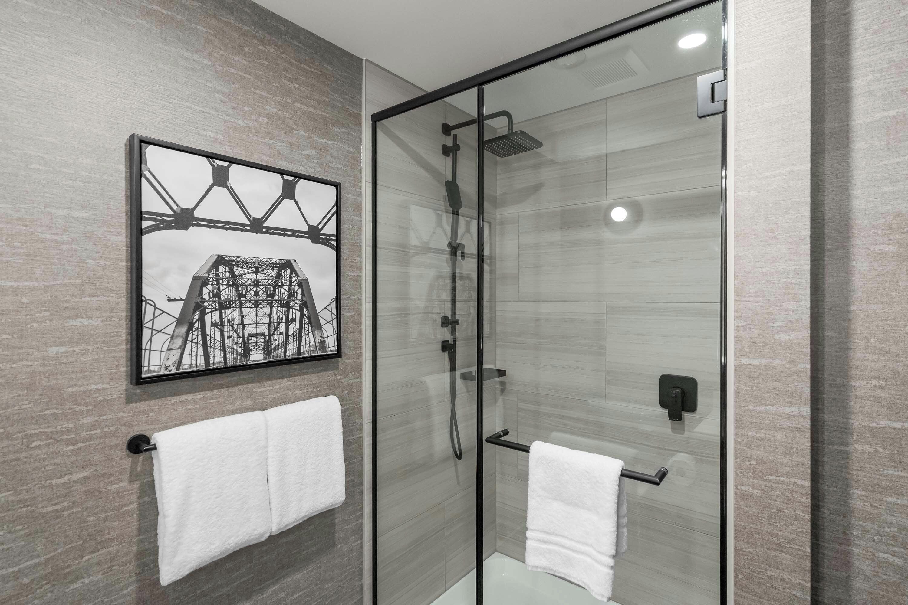 Une salle de bain moderne avec une douche à parois de verre, un porte-serviettes et un tableau encadré au mur.