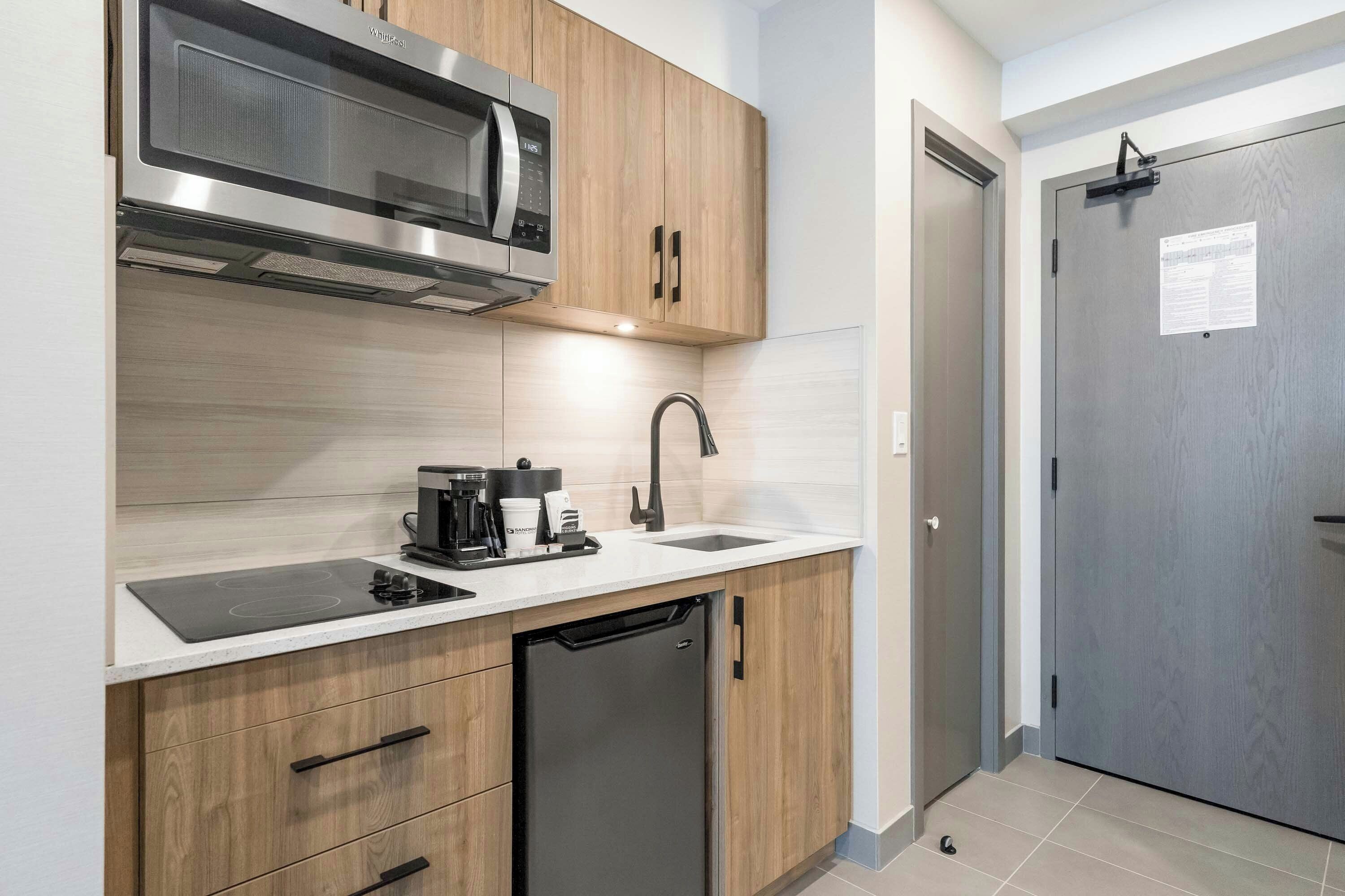 A compact kitchen with a built-in microwave, a coffee maker, and a dishwasher.