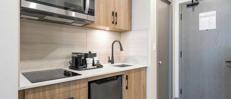 A compact kitchen with a built-in microwave, a coffee maker, and a dishwasher.