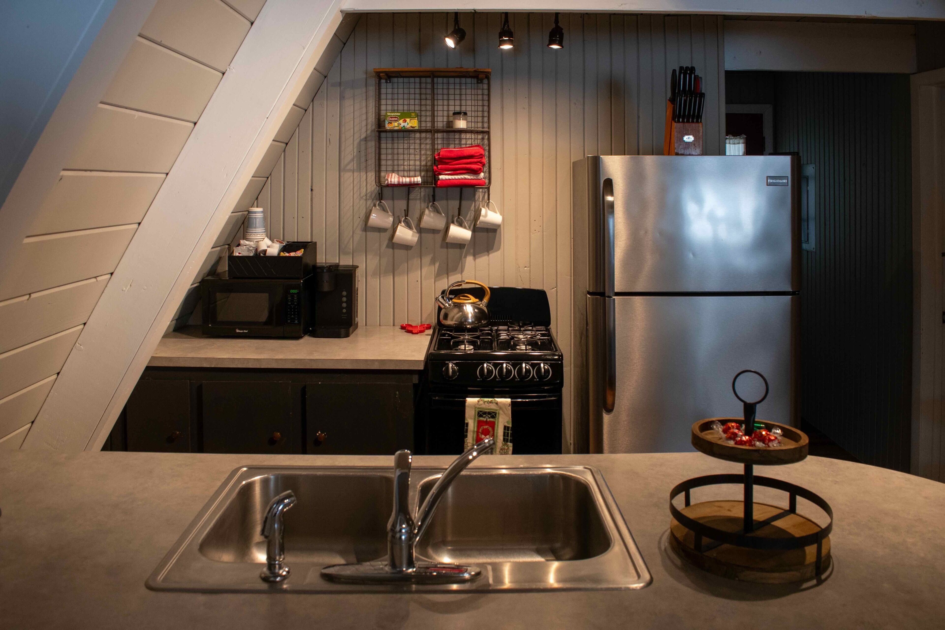 A kitchen with a stainless steel sink, a stove, and a refrigerator.
