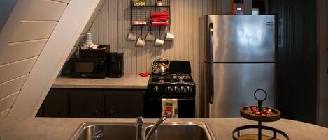 A kitchen with a stainless steel sink, a stove, and a refrigerator.