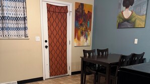 Un comedor con una mesa, sillas, un ventilador de techo y un cuadro en la pared.