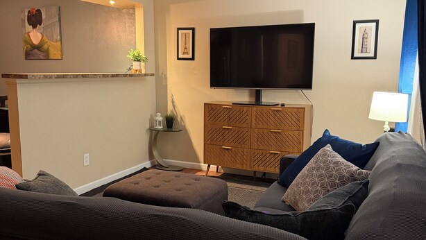 Una sala de estar con un sofá, un televisor, un mueble y una lámpara.